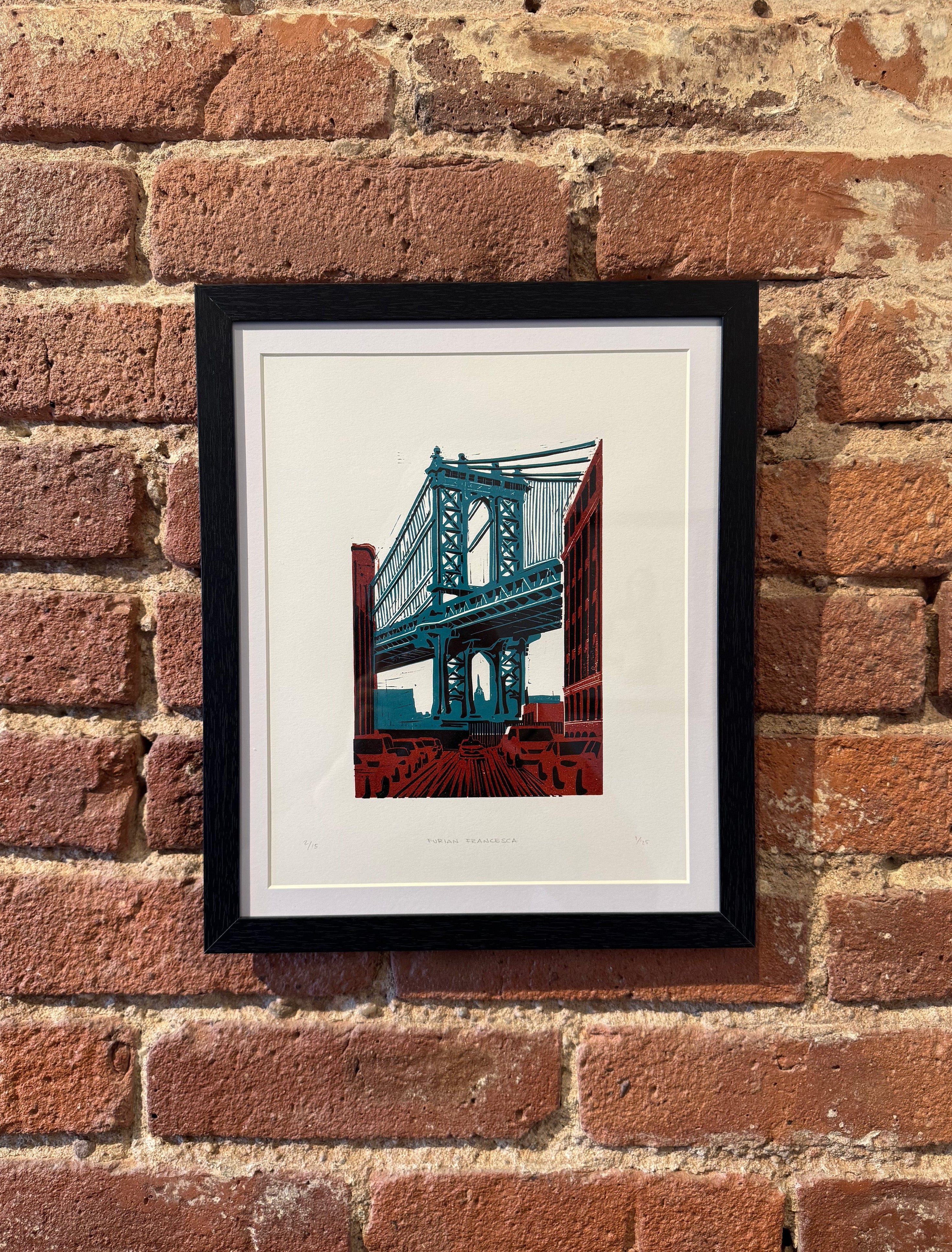 Framed artwork of a bridge on a brick wall