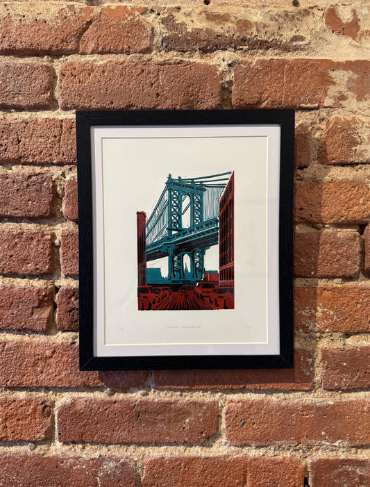 Framed artwork of a bridge on a brick wall