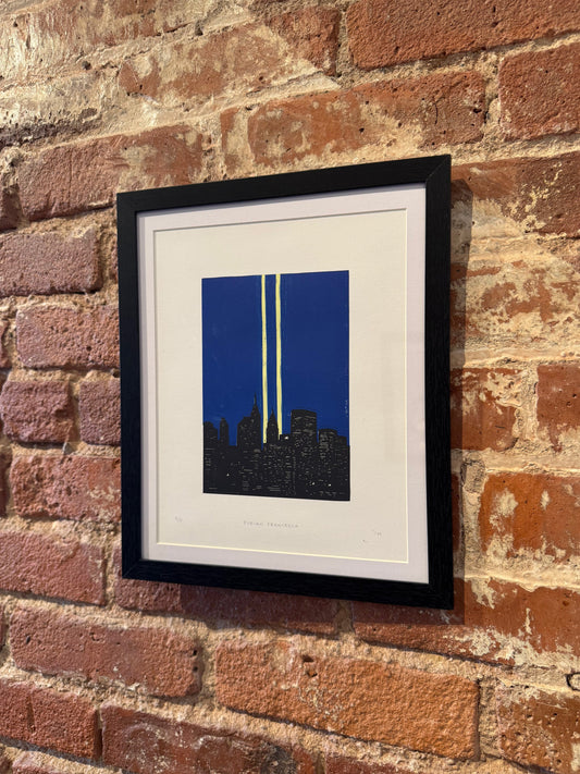 Framed artwork with a blue background and white lines on a brick wall.